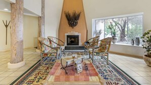 Una sala de estar acogedora con chimenea, alfombra estampada y sillones de mimbre.