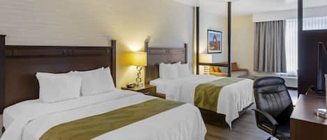 A hotel room with two beds, a desk, a chair, and a television.