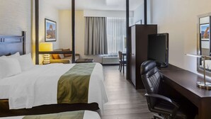 Una habitación de hotel con una cama grande, un escritorio con una silla, un televisor y un aire acondicionado.