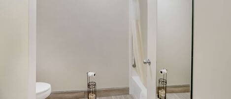 Une salle de bain moderne équipée de toilettes, d’une douche à parois de verre et d’un miroir qui reflète l’espace de la douche.