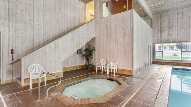 Una piscina interior con revestimiento de madera, una escalera y zonas de estar.