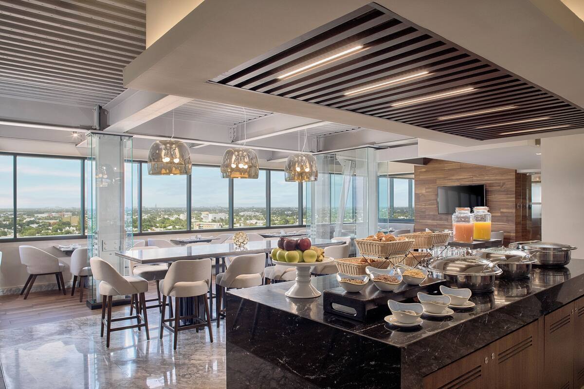 Una cocina moderna con una isla grande, barra de desayuno y amplios ventanales con vistas a la ciudad.