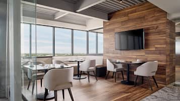 Un área de comedor moderna con paredes de vidrio, paneles de madera y un televisor de pantalla plana.