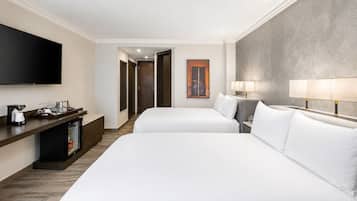 Habitación de hotel con dos camas, televisión, minibar y un cuadro en la pared.