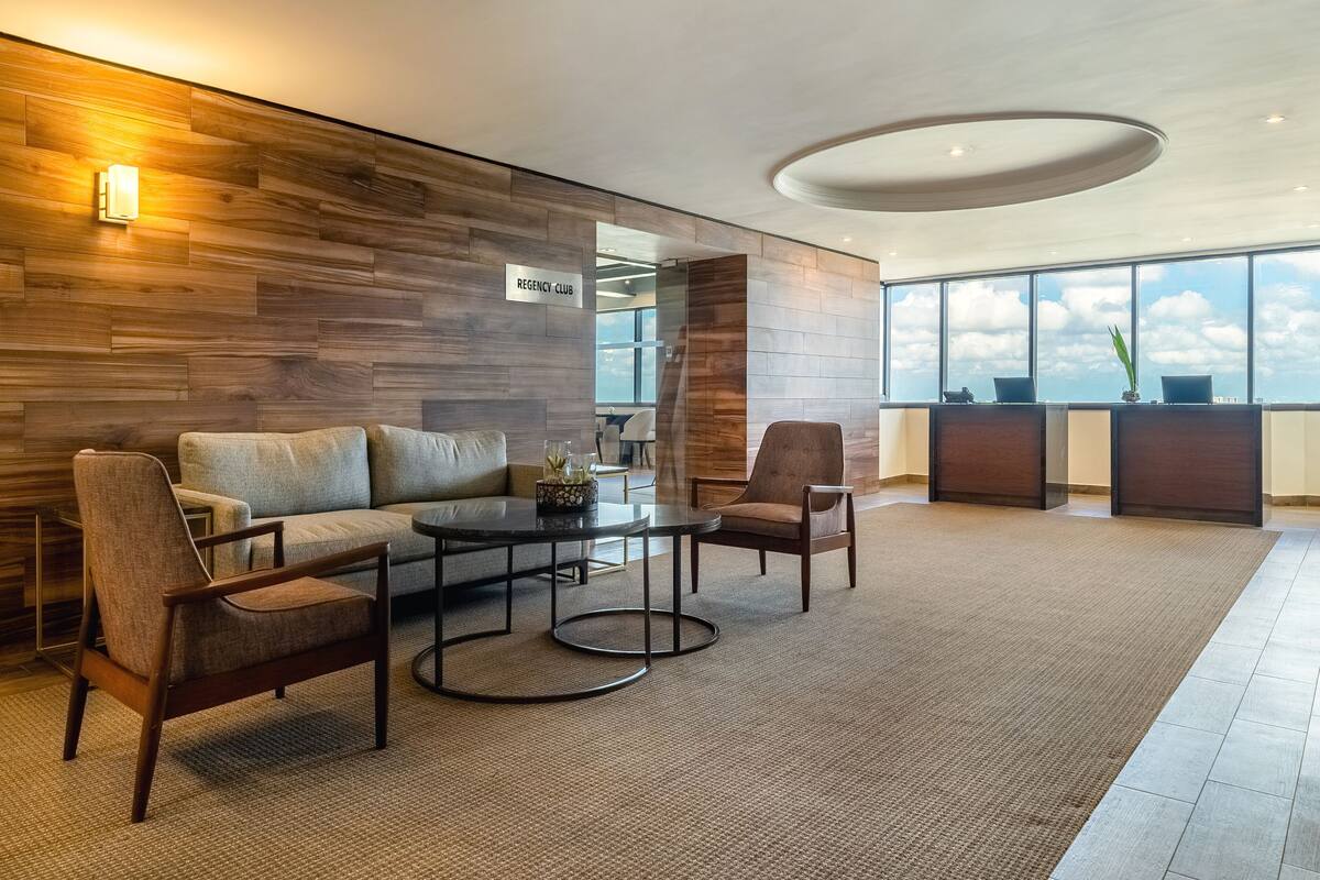 Un vestíbulo moderno con una pared de madera, una recepción, un sofá y una mesa de centro.
