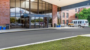 Um hotel Comfort Inn com fachada de vidro moderna, área de estacionamento e uma van Go Stay LITE.