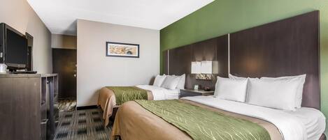 Ein Hotelzimmer mit zwei Betten, einem Schreibtisch mit Fernseher, einer gerahmten Karte an der Wand und einer Wand in Grünton.