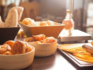 Un bufé de desayuno con diversas opciones de panadería, incluyendo pan, cruasanes y bollería.