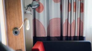 Une pièce avec une porte en bois, un banc rouge et une lampe fixée au mur.