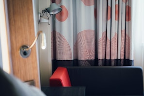A room with a wooden door, a red bench, and a wall-mounted lamp. - Novotel Coventry M6/J3 (Coventry)