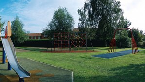 A playground with a slide, swings, and climbing structures. - Novotel Coventry M6/J3 (Coventry)