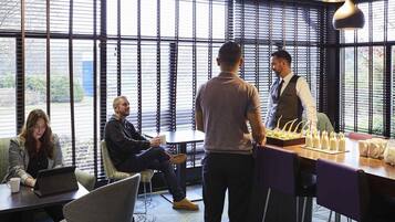 Ein moderner Büroraum mit großen Fenstern, einem Konferenztisch und einer Bar mit Getränken.