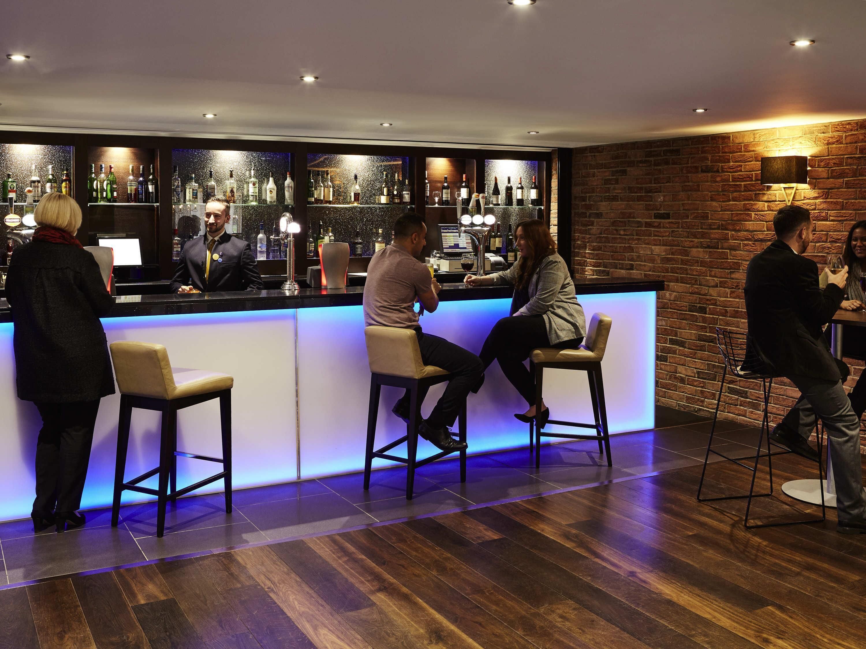 A bar area with a counter, stools, and a brick wall.