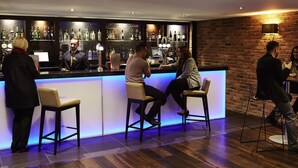 Un espace bar avec un comptoir, des tabourets et un mur en briques.