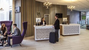 A hotel lobby with a reception desk, seating area, and a staircase. - Novotel Coventry M6/J3 (Coventry)