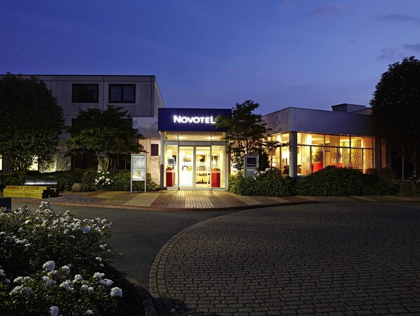 Un hotel con fachada moderna, un acceso bien iluminado y un camino de entrada pavimentado.