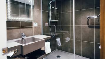 Un baño moderno con tocador, espejo y ducha.