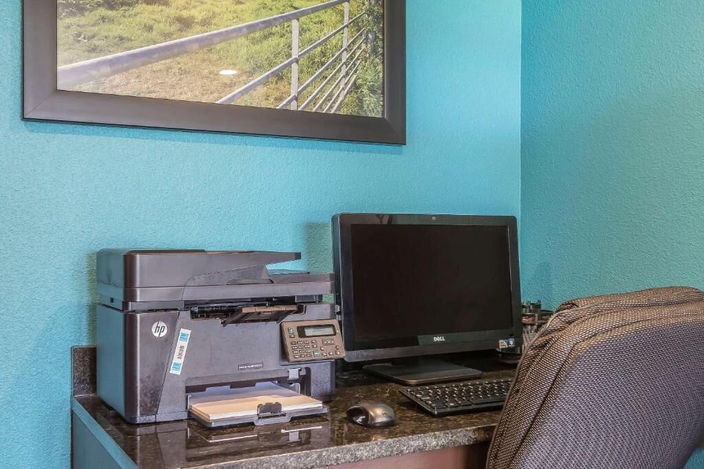 Un escritorio con una impresora HP, un monitor Dell y un teclado.