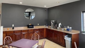 Una cocina moderna con paredes oscuras, una encimera de madera y un espejo redondo.