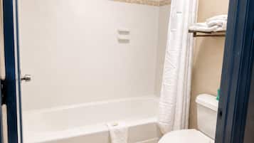 Un baño con una bañera blanca, un inodoro y una cortina de ducha.