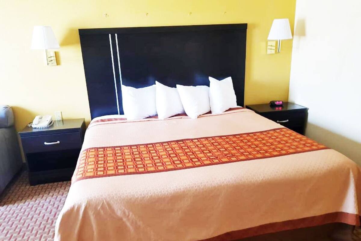 A neatly made bed with a patterned bedspread, two bedside tables with lamps, and a telephone on the left table.