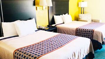 A hotel room with two beds, each with a headboard, bedside lamps, and a patterned bedspread.