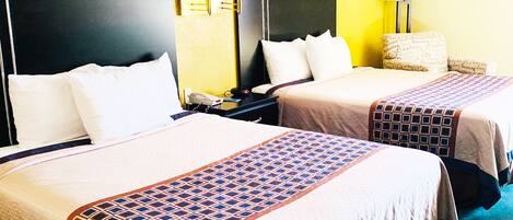A hotel room with two beds, each with a headboard, bedside lamps, and a patterned bedspread.