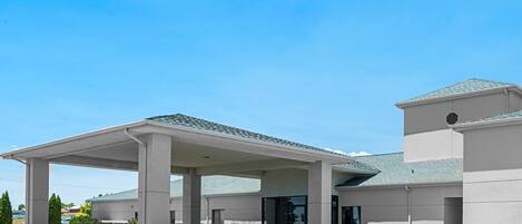 A modern building with a covered entrance, large columns, and a sloped roof.