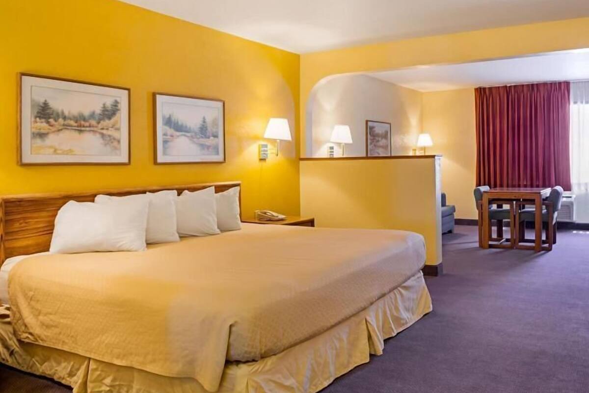 Habitación de hotel con una cama grande, dos lámparas de noche, un escritorio con una silla y dos cuadros en la pared.