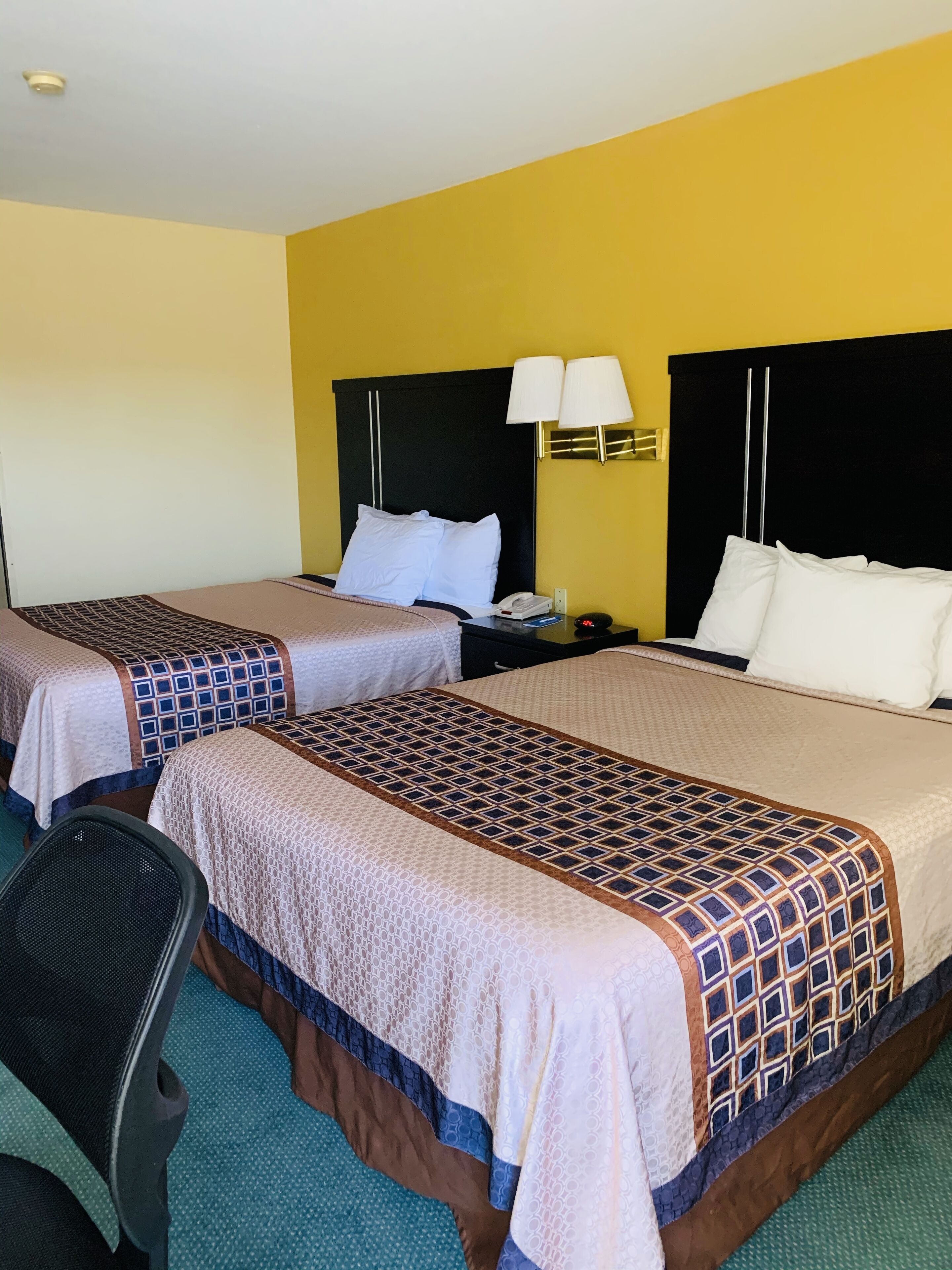 Une chambre d’hôtel avec deux lits, un bureau et une chaise.