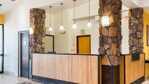 Un mostrador de recepción con fachada de piedra, paneles de madera e iluminación colgante.