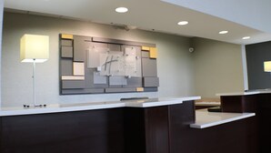Un mostrador de recepción de hotel con un diseño moderno, un letrero de Holiday Inn Express y dos lámparas de pie.