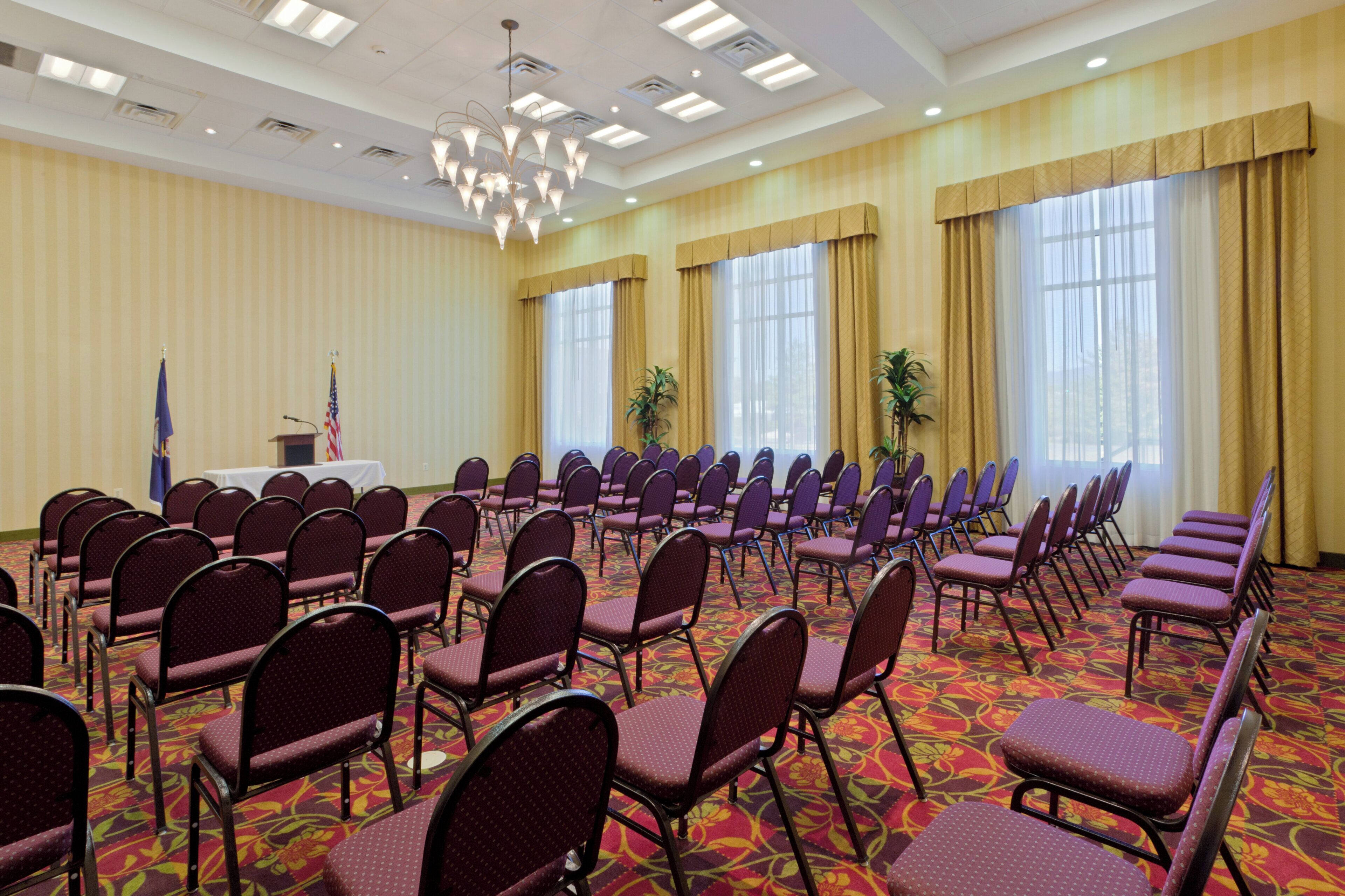A conference room with rows of chairs, a podium, and an American flag.