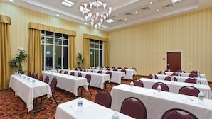 A conference room with multiple tables, chairs, and water bottles, featuring a chandelier and large windows. - Holiday Inn Express Woodstock-Shenandoah Valley by IHG (Woodstock)