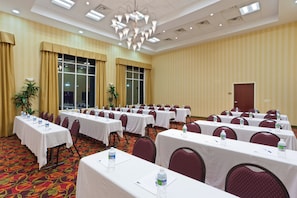 A conference room with multiple tables, chairs, and water bottles, featuring a chandelier and large windows. - Holiday Inn Express Woodstock-Shenandoah Valley by IHG (Woodstock)