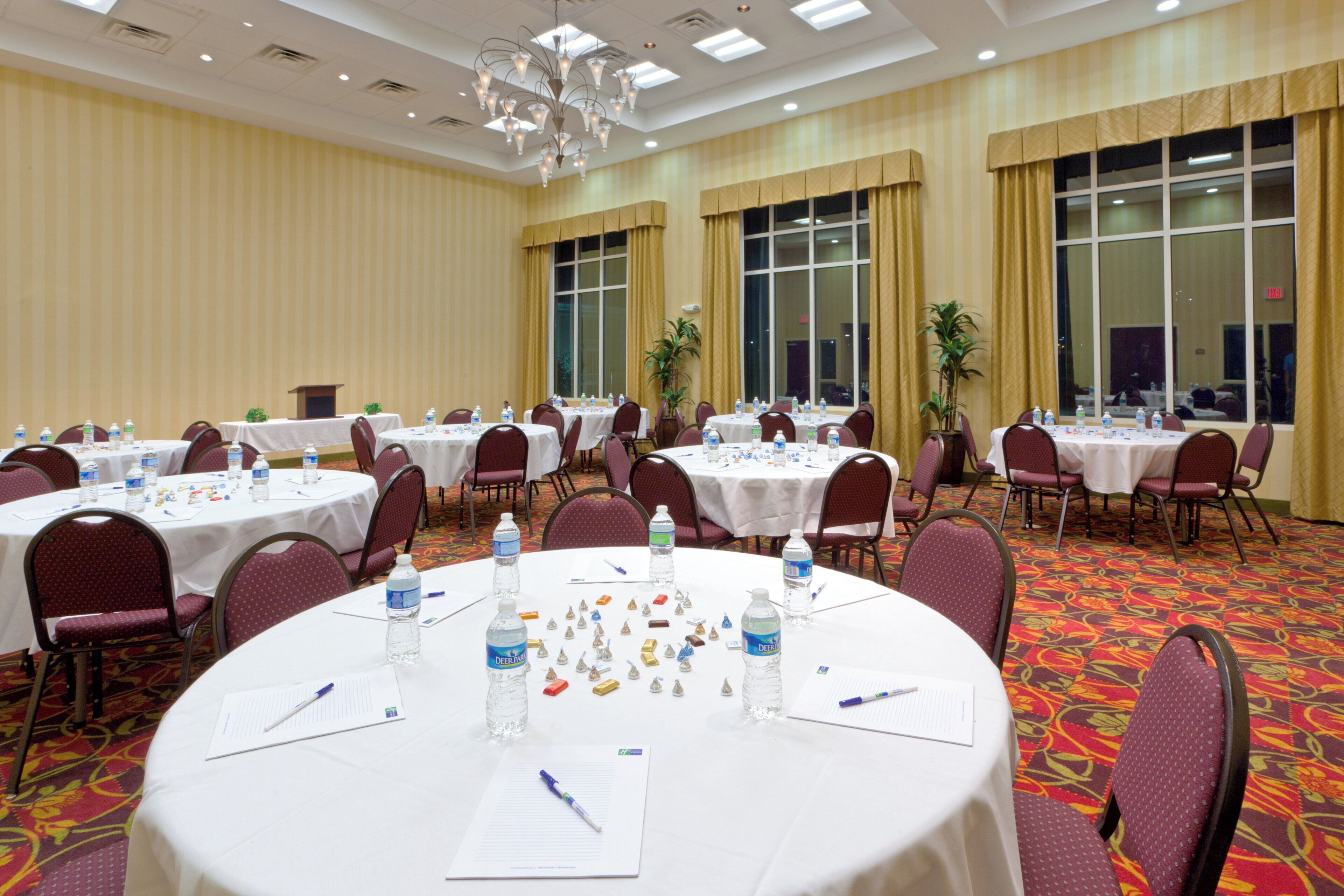 A conference room with round tables, chairs, water bottles, and Deja Blue pens.