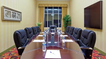 A conference room with a long table, chairs, water bottles, and a plant.