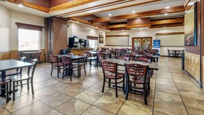 A spacious dining area with multiple tables and chairs, wooden beams on the ceiling, and a view of the outdoors through a window. - Best Western Prescottonian (Prescott)