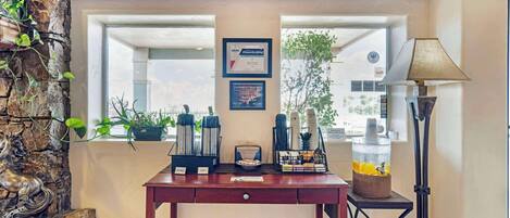 A reception desk with a coffee station, framed certificates, and a lamp.