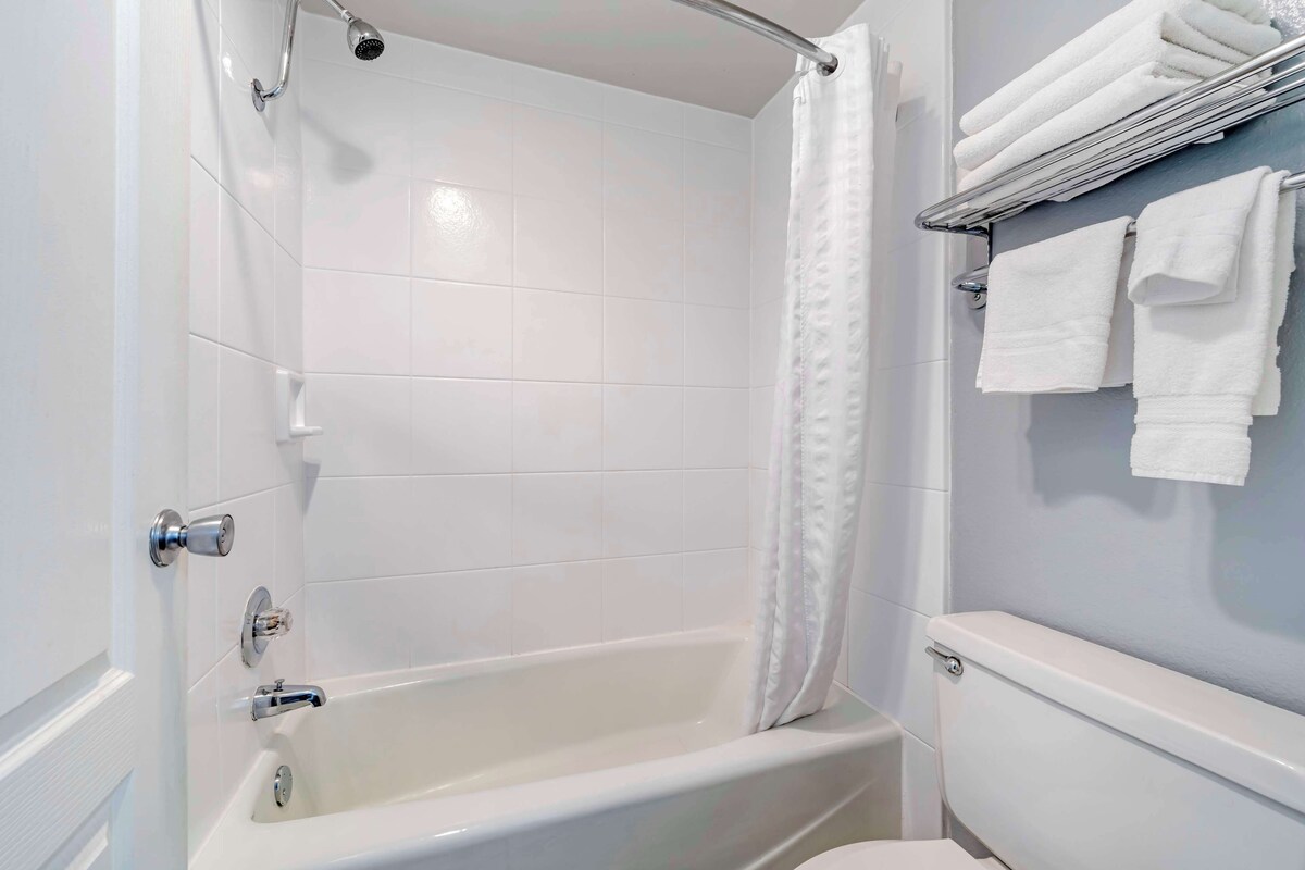 A bathroom with a bathtub, a toilet, and a towel rack with towels.