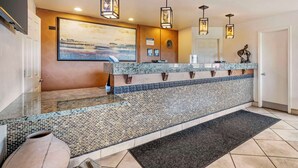 A reception area with a tiled floor, a reception desk, a large painting, and pendant lighting. - Best Western Prescottonian (Prescott)