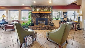 A cozy living room with a stone fireplace, leather chairs, a coffee table, and a dining area with a table and chairs. - Best Western Prescottonian (Prescott)