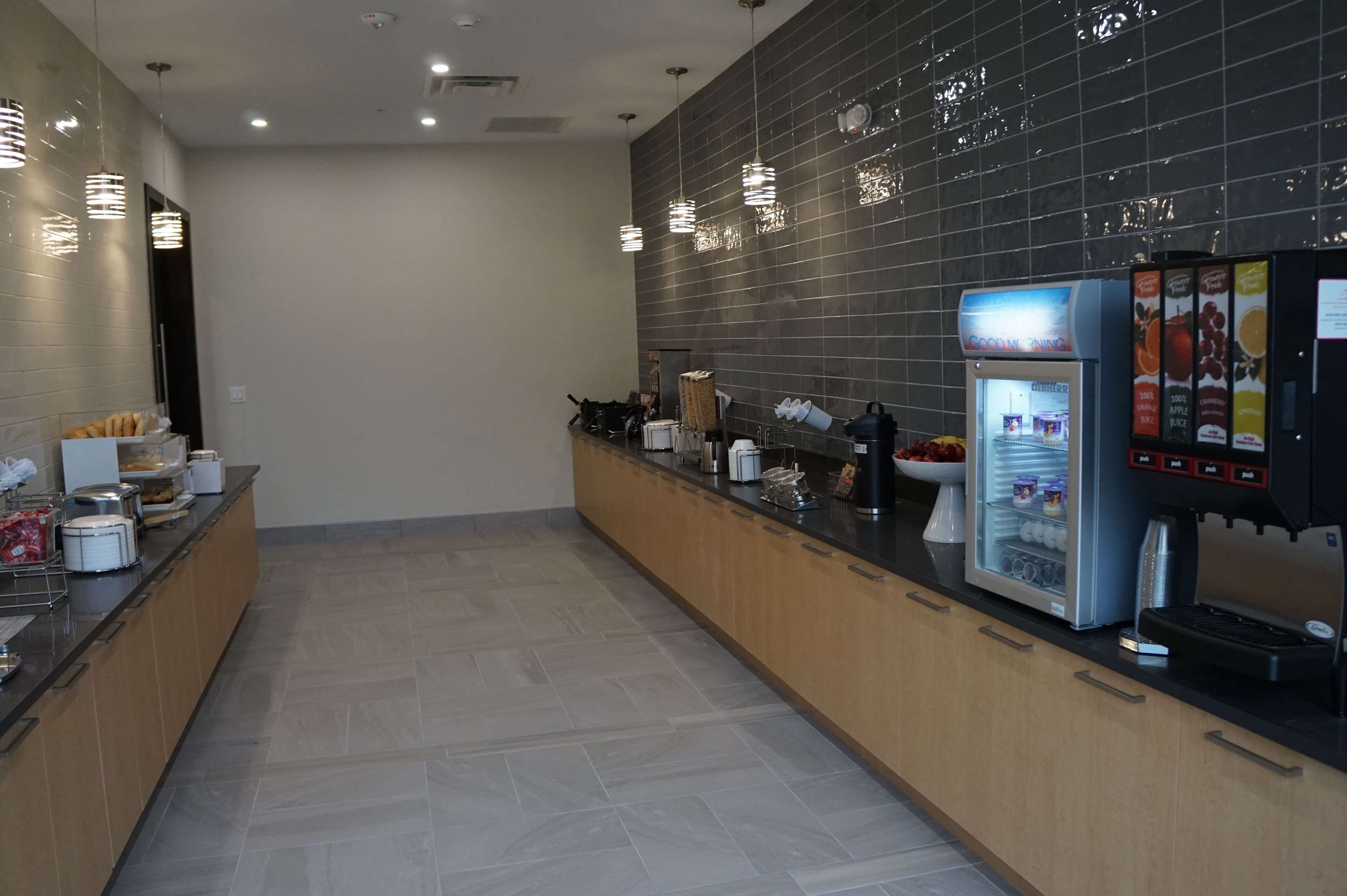 A modern kitchen area with a coffee machine, a refrigerator, and various food items on the counter.