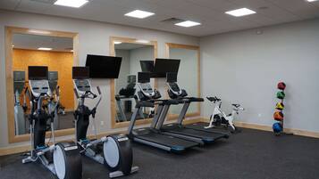 Un gimnasio con bicicletas estáticas, cintas de correr y una máquina de remo.