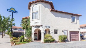 A Days Inn building with two office entrances, a garage, and a clear blue sky. - Days Inn by Wyndham Castaic Six Flags Magic Mountain (Castaic)