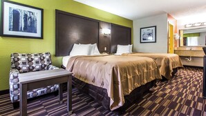 A hotel room with two beds, a sofa, a small table, and a bathroom with a mirror. - Quality Inn Albemarle (Albemarle)