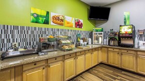 A kitchen with a breakfast bar, a coffee machine, and a flat-screen TV mounted on the wall. - Quality Inn Albemarle (Albemarle)