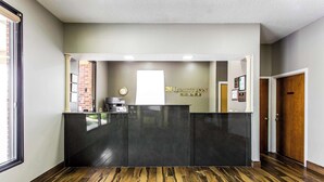 A reception desk with a dark countertop and a clock above it. - Quality Inn Albemarle (Albemarle)