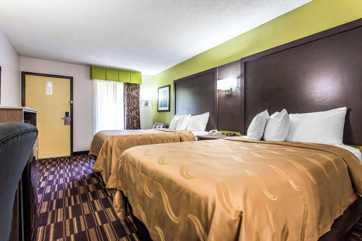 Habitación de hotel con dos camas, un escritorio y una silla.