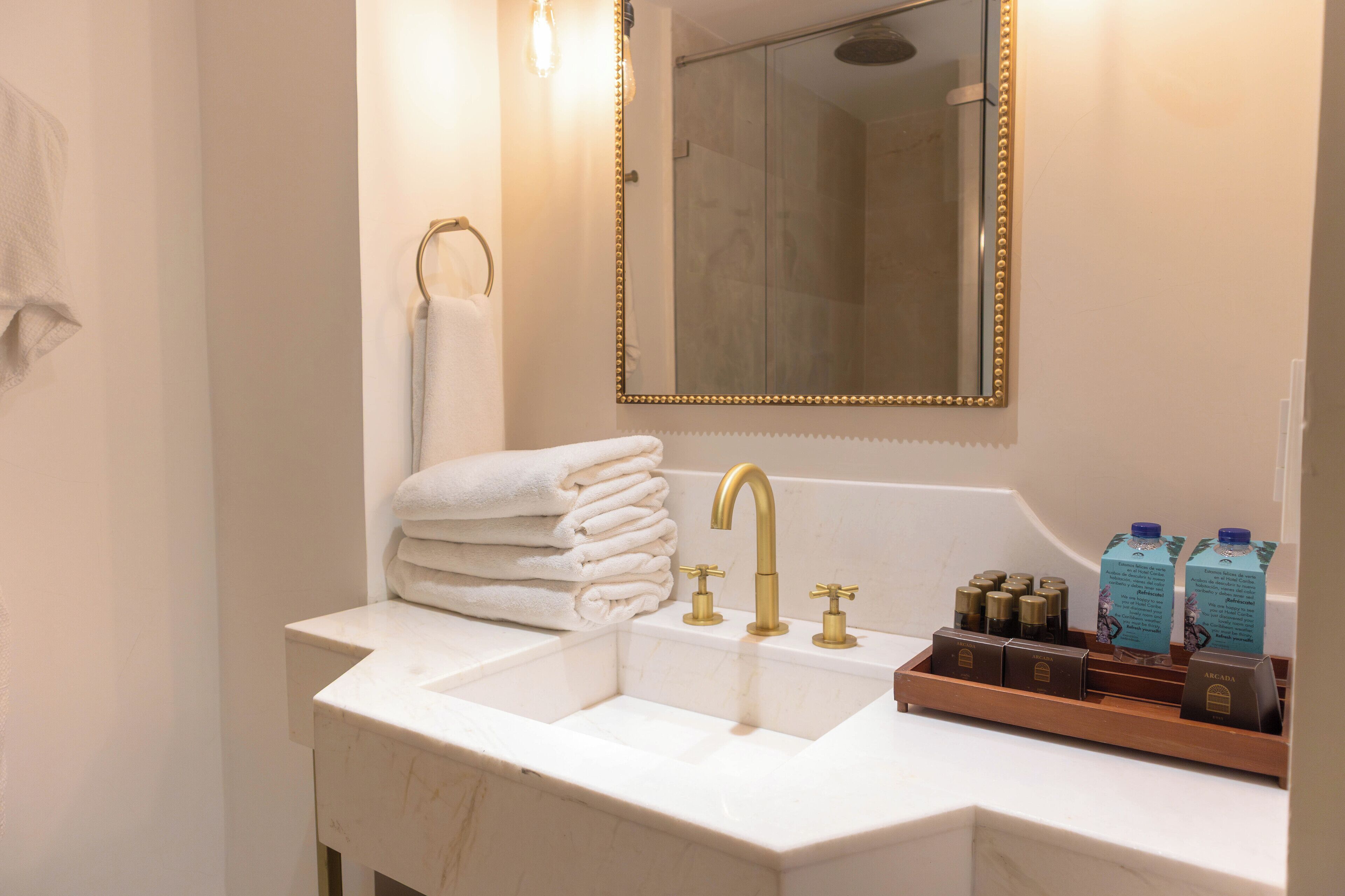 A bathroom with a white sink, gold faucets, a mirror with a gold frame, and a towel rack.